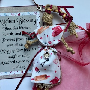 Op de afbeelding: Een keukenzegenbord met een jute achtergrond en een bordeauxrode rand. Het bord heeft een gedicht met de tekst: "Zegen deze keuken, haard en huis. Bescherm tegen morsen, verlicht alle stress. Moge vreugde vrij stromen, laat lachen blijven. Een heilige ruimte dag en nacht."