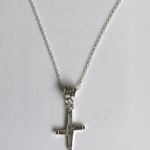May include: A silver chain necklace with a silver Celtic cross pendant.