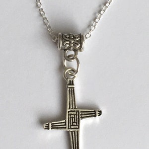 May include: A silver chain necklace with a silver Celtic cross pendant. The cross is detailed with intricate designs.