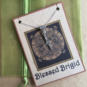 May include: A silver necklace with a Celtic cross pendant. The pendant is on a card with the text "Blessed Brigid".