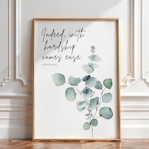 Könnte beinhalten: Gerahmter Kunstdruck mit goldenem Rahmen. Der Druck zeigt den Text "Indeed, with hardship comes ease" und einen Aquarell-Eukalyptuszweig. Der Text ist in schwarzer Schrift, und der Eukalyptus ist in Grün- und Blautönen gehalten.