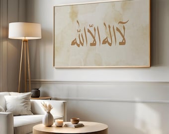 May include: A rectangular wall art piece featuring brown Arabic calligraphy centered on a textured, cream-colored background with subtle watercolor-style tan splotches, all enclosed within a thin, metallic gold frame.