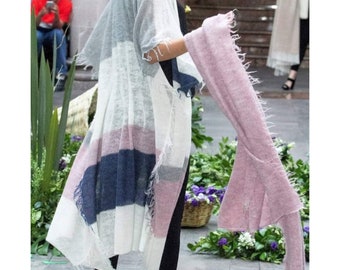 May include: A long, open-front cardigan with a color block design in white, light pink, and navy blue. The cardigan has a fringed hem and sleeves. A matching light pink scarf is held in the hand.