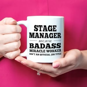 May include: White ceramic coffee mug with black text that reads "Stage Manager because badass miracle worker isn't an official job title."