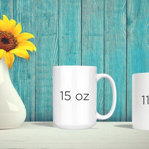 May include: Two white ceramic mugs with black text. The mug on the left says "15 oz" and the mug on the right says "11 oz".