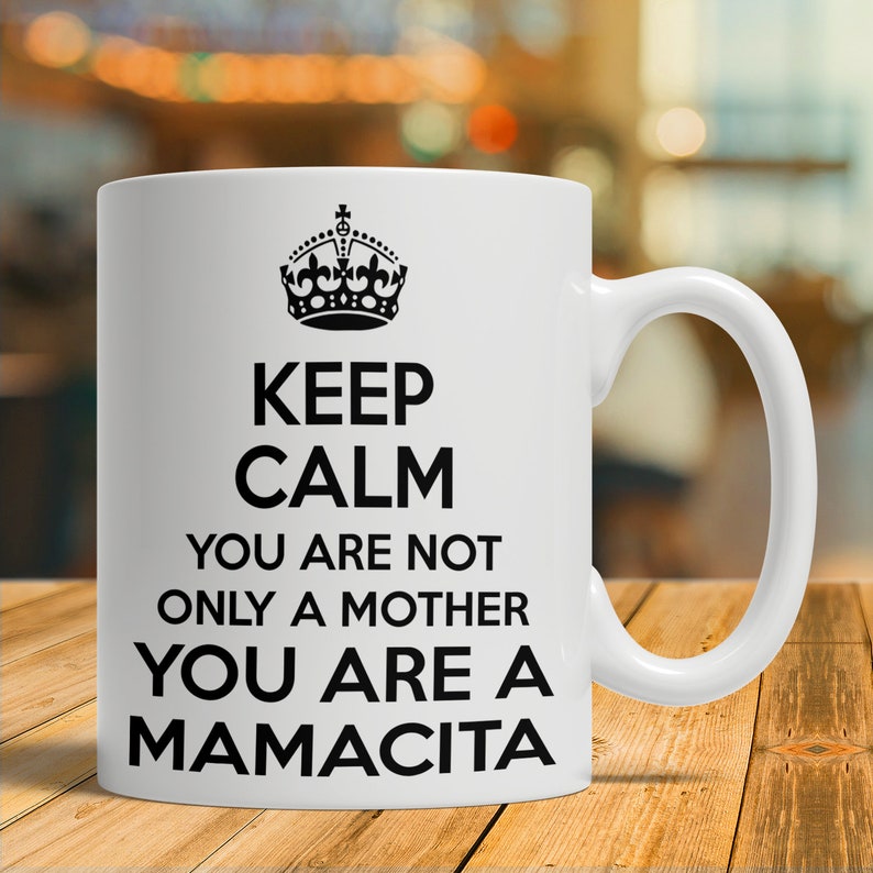 May include: White ceramic mug with a black crown and the text "Keep Calm You Are Not Only A Mother You Are A Mamacita".