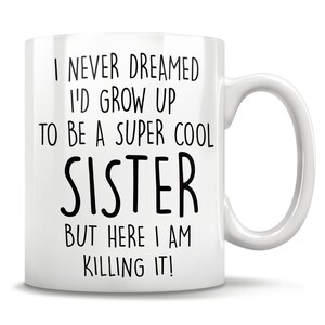 Puede incluir: Taza de caf&eacute; de cer&aacute;mica blanca con texto negro que dice "Nunca so&ntilde;&eacute; con crecer para ser una hermana s&uacute;per genial, pero aqu&iacute; estoy, &iexcl;mat&aacute;ndolo!"