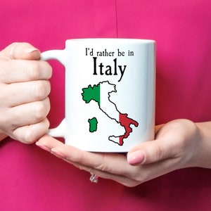 Puede incluir: Taza de cer&aacute;mica blanca con un contorno negro de Italia y los colores de la bandera italiana. El texto en la taza dice "I'd rather be in Italy".