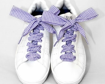 May include: White leather sneakers with purple and white gingham ribbon laces tied in a bow.