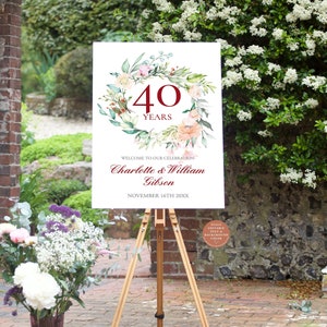 Puede incluir: Un cartel blanco con una corona de acuarela de vegetación y flores. El número 40 está en el centro de la corona en texto rojo. El texto "YEARS" está debajo del número 40. El texto "WELCOME TO OUR CELEBRATION" está debajo de la corona. Los nombres "Charlotte & William Gibson" están debajo del texto "WELCOME TO OUR CELEBRATION". La fecha "NOVEMBER 16TH 20XX" está debajo de los nombres.