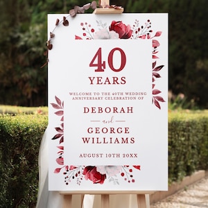 Puede incluir: Un letrero blanco sobre un caballete de madera, decorado con detalles florales burdeos. El letrero dice "40 AÑOS" y da la bienvenida a los invitados a la celebración del 40 aniversario de boda de Deborah y George Williams, 10 de agosto de 20XX.