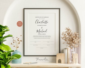 May include: A framed certificate of marriage with the names Charlotte Elizabeth Foden and Michael Daniel Gibson. The certificate is printed on white paper with black text and is framed in a gray frame.