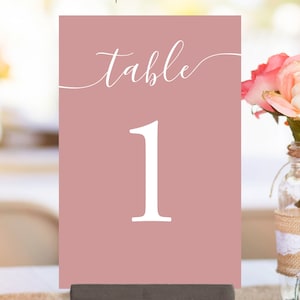 May include: Dusty rose table number card with white calligraphy that says "Table 1".
