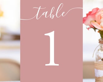 May include: Dusty rose table number card with white calligraphy that says "Table 1".