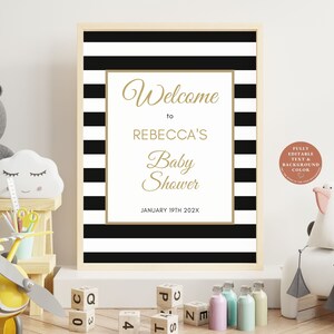 K&ouml;nnte beinhalten: Ein bedruckbares Schild mit schwarzen und wei&szlig;en Streifen und goldener Schrift, auf dem "Willkommen zu Rebeccas Babyparty am 19. Januar 202X" steht. Das Schild ist in einem hellen Holzrahmen gerahmt.