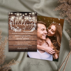 May include: Rustic wedding invitation with a woodgrain background and fairy lights. The invitation features a white floral wreath with the words "The Wedding of" in a script font. The couple's names, wedding date, and location are listed below the wreath. A photo of the couple is included on the right side of the invitation.