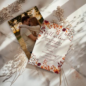 May include: Two wedding announcement cards. One features a couple embracing, the other has the text "fall in love" with floral accents. The text reads "Save the Date for the Wedding of Elizabeth and James, October 21st 20XX, Jackson, MS."