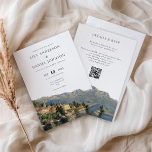 Peut inclure: Ensemble de faire-part de mariage avec un paysage de lac et de bâtiments. L'invitation comprend les noms Lily Anderson & Daniel Johnson, la date du 15 septembre 2035 et les détails de la réponse. L'ensemble est sur fond blanc avec une brindille d'herbe séchée.