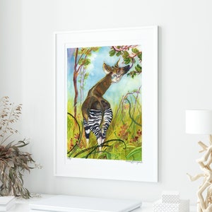 May include: A watercolor painting of an okapi, a mammal native to the Democratic Republic of Congo, standing in a lush green forest. The okapi is brown and white with a striped pattern on its hindquarters. The painting is framed in a white frame.