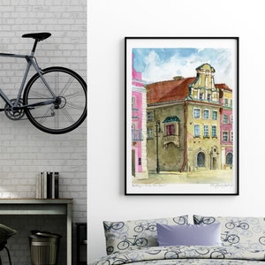 May include: A watercolor painting of a building with a pink facade and a brown roof. The building has a balcony with a wrought iron railing and a sign that says "Brauerei". The painting is framed in black and hanging on a white wall.