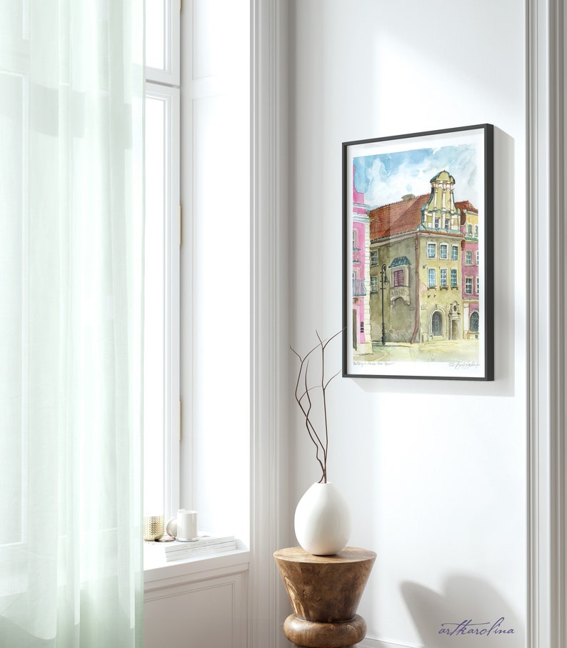 May include: Watercolor painting of a colorful building with a unique architectural design. The building is painted in shades of pink, yellow, and brown, with a white balcony and a decorative roof. The painting is framed in black and has a white mat.