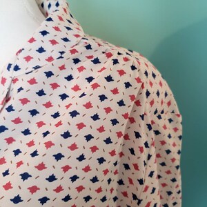 May include: A white blouse with a collar and a pattern of red and blue geometric shapes.