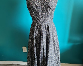 May include: A black off-the-shoulder dress with a floral print featuring pink and green flowers. The dress has a fitted bodice and a full skirt.