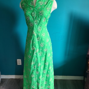 May include: A sleeveless maxi dress with a V-neckline and a floral print. The dress is green with pink and white flowers.