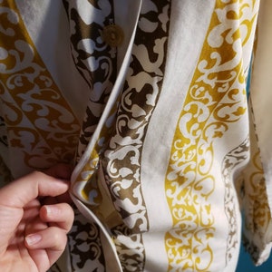 May include: A white button-up shirt with a vertical striped pattern. The stripes are a dark brown and a mustard yellow. The shirt has a button closure and a collar.