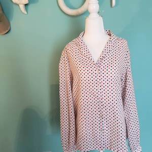 May include: A white long-sleeved button-up shirt with a geometric pattern in red, blue, and white.