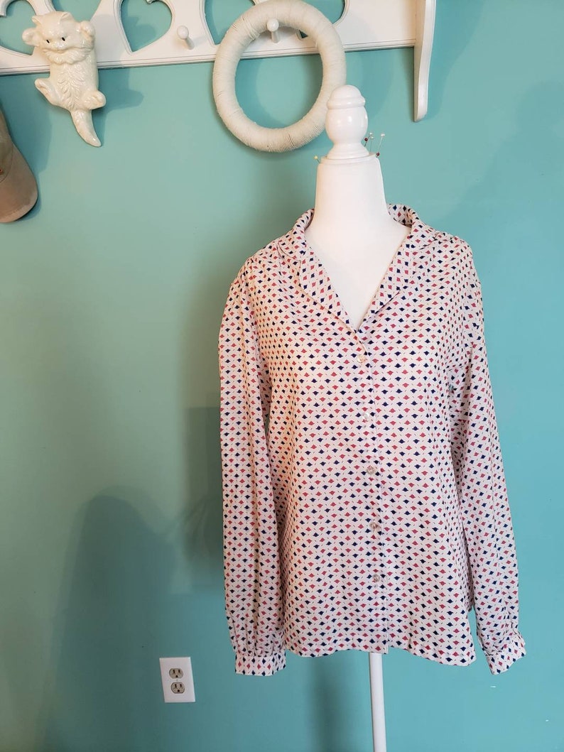 May include: A white long-sleeved button-up shirt with a geometric pattern in red, blue, and white.