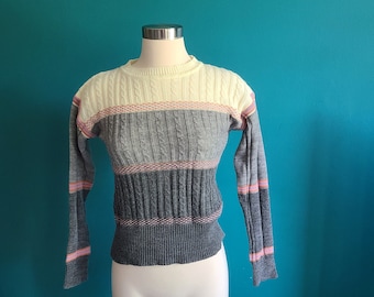 May include: A striped knit sweater with long sleeves. The sweater is gray, white, and pink.
