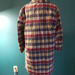 May include: A long-sleeved plaid shirt in shades of red, green, blue, and white. The shirt has a button-down collar and long sleeves.