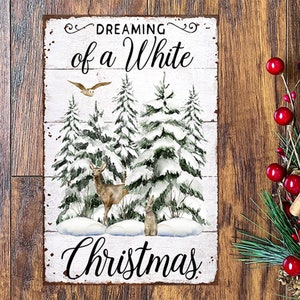 May include: A rectangular metal sign with the words "Dreaming of a White Christmas" in black script. The sign features a winter scene with snow-covered pine trees, a deer, a rabbit, and an owl. The sign has a distressed, rustic look.