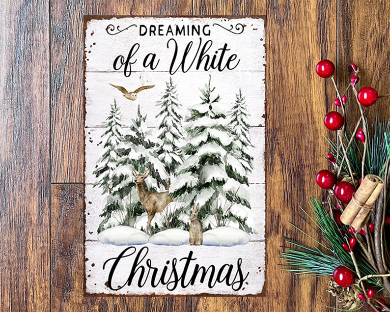 May include: A rectangular metal sign with the words "Dreaming of a White Christmas" in black script. The sign features a winter scene with snow-covered pine trees, a deer, a rabbit, and an owl. The sign has a distressed, rustic look.