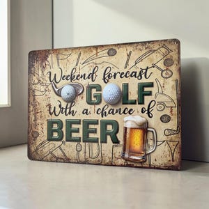 May include: A rectangular metal sign with a distressed, vintage-style finish. The text reads "Weekend forecast GOLF With a chance of BEER". It features illustrations of golf clubs, balls, and a mug of beer, with two physical golf balls attached.