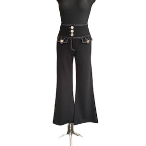 Puede incluir: Pantalón negro de cintura alta acampanado con detalles de costura blanca y botones dorados.