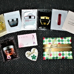 Puede incluir: Una colección de productos de belleza en tamaños de muestra, que incluyen cremas faciales, base líquida y perfume. Los productos están dispuestos sobre un fondo negro con una pequeña caja de regalo envuelta en papel de lunares verde y rojo con una cinta dorada.