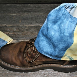 May include: Brown leather boot with a blue denim and peach-patterned boot cover. A second boot cover with blue and yellow stripes is next to the boot. The boot covers have elastic openings.