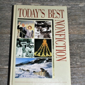 May include: A beige book with the title "Today's Best Nonfiction" in red lettering. The cover features a collage of five images: a couple in front of a microphone, a black and white image of people in a crowd, a gold necklace, and a dog sledding team in a snowy landscape.