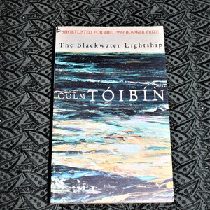 May include: A book cover with a blue and white abstract painting of water. The title is "The Blackwater Lightship" by Colm Tóibín. The book was shortlisted for the 1999 Booker Prize.