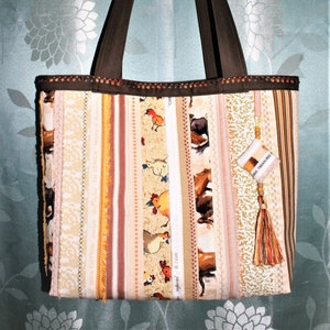 May include: A brown tote bag with a patchwork design featuring various fabrics with chickens, horses, and floral patterns. The bag has brown straps and a small brown fabric charm with the text "Little Treasures".