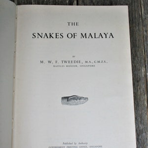 May include: The cover of a book titled "The Snakes of Malaya" by M. W. F. Tweedie, M.A., C.M.Z.S., Raffles Museum, Singapore. The book was published by Authority, Government Printing Office, Singapore.