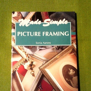 May include: A book titled "Made Simple Picture Framing" by Sonia Aarons. The cover features a close-up of various picture frames in gold, silver, and wood.