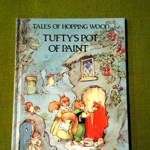 Puede incluir: Una portada de libro con el título "Tales of Hopping Wood Tufty's Pot of Paint" de Rene Cloke. La portada presenta una ilustración de dos ardillas pintando una puerta roja en una casa de piedra.