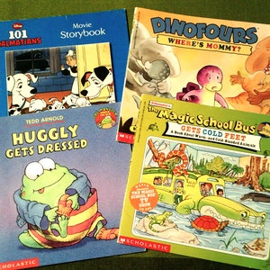 May include: A collection of four children's books featuring colourful illustrations. The books are titled "101 Dalmatians Movie Storybook", "Dinofours Where's Mommy?", "Huggly Gets Dressed", and "The Magic School Bus Gets Cold Feet".