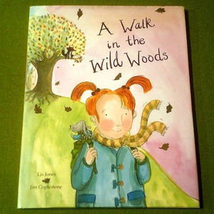 May include: A children's book cover with a watercolor illustration of a girl with red hair and a blue coat walking in the woods with a dog. The title of the book is "A Walk in the Wild Woods".