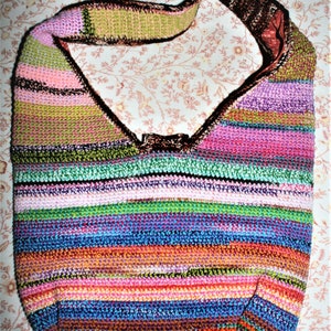 K&ouml;nnte beinhalten: Eine bunte gestreifte geh&auml;kelte Umh&auml;ngetasche mit einem braunen Riemen. Die Tasche ist aus verschiedenen Farben gefertigt, darunter Pink, Gr&uuml;n, Blau und Orange.