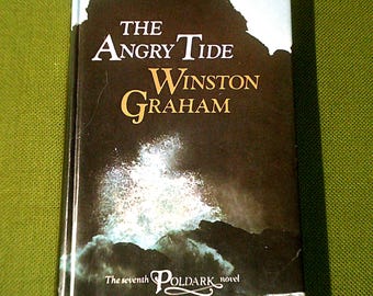 Könnte beinhalten: Das siebte Buch der Poldark-Reihe, "The Angry Tide" von Winston Graham, zeigt ein dramatisches Bild einer brechenden Welle an einer felsigen Küste.