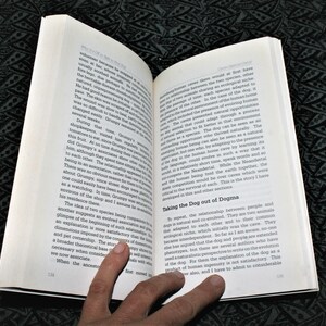 May include: A close-up of a book page with text about the relationship between humans and dogs. The text discusses the co-evolution of the two species and how they adapted to each other's environments. The book is open and the pages are slightly curled.